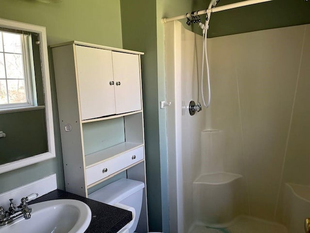 bathroom with toilet, a stall shower, and a sink