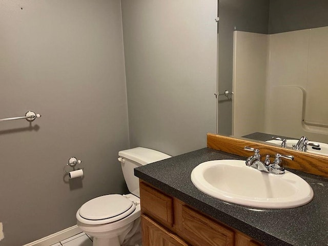 bathroom featuring tile patterned floors, baseboards, vanity, and toilet