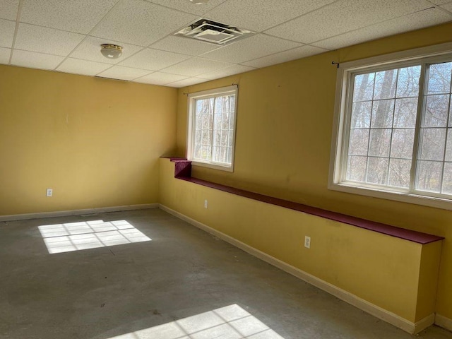 spare room with baseboards, a paneled ceiling, visible vents, and concrete flooring