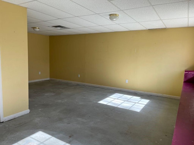 spare room with visible vents, baseboards, concrete floors, and a drop ceiling