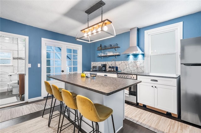 134 Courtland St, Providence, RI 02909 - kitchen with stainless steel appliances, wall chimney range hood, dark countertops, and wood finished floors