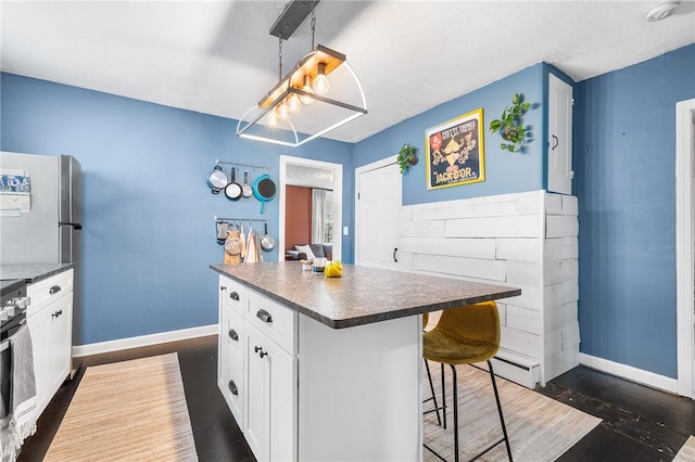134 Courtland St, Providence, RI 02909 - kitchen with baseboards, dark countertops, dark wood-type flooring, and a breakfast bar