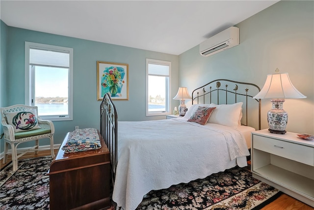 183 Twin Peninsula Ave, South Kingstown, RI 02879 - bedroom with a wall unit AC, wood finished floors, and baseboards