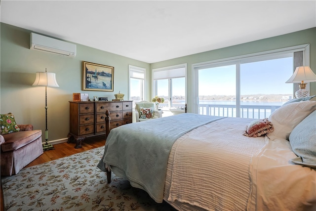 183 Twin Peninsula Ave, South Kingstown, RI 02879 - bedroom with a wall unit AC, access to outside, wood finished floors, a water view, and baseboards