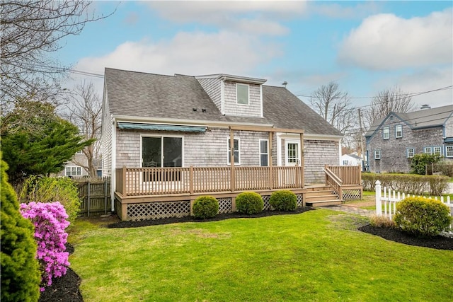rear view of house with fence, a lawn, a shingled roof, and a deck