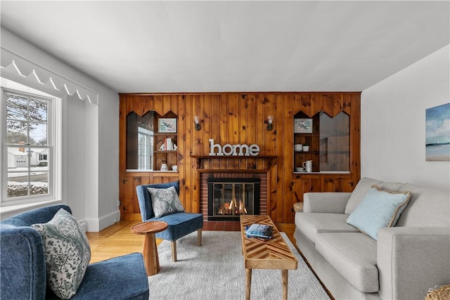 living room featuring a fireplace, wood finished floors, wood walls, and baseboards