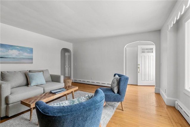 living room featuring a baseboard heating unit, arched walkways, and light wood-type flooring