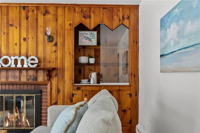 interior details featuring a brick fireplace, wood walls, and baseboards