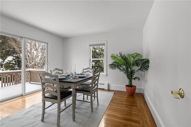 dining space featuring wood-type flooring, a baseboard radiator, and baseboards
