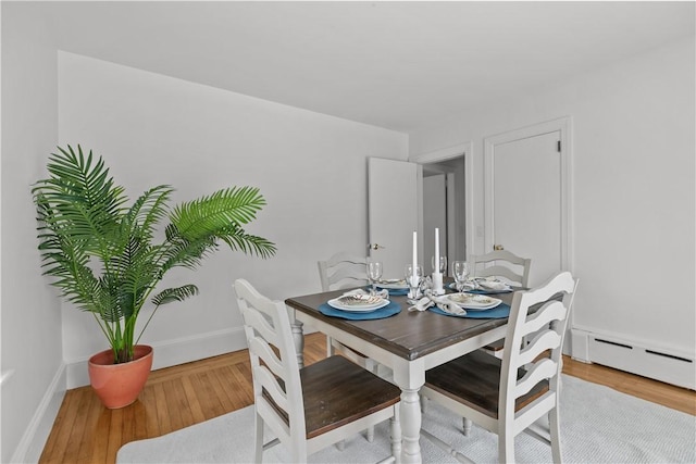 dining area featuring baseboard heating, baseboards, and wood finished floors