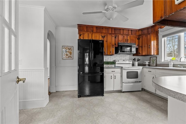 kitchen featuring tasteful backsplash, a sink, black appliances, ceiling fan, and arched walkways