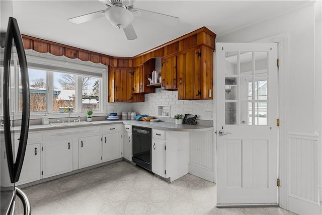 kitchen featuring light countertops, a sink, black dishwasher, tasteful backsplash, and ceiling fan