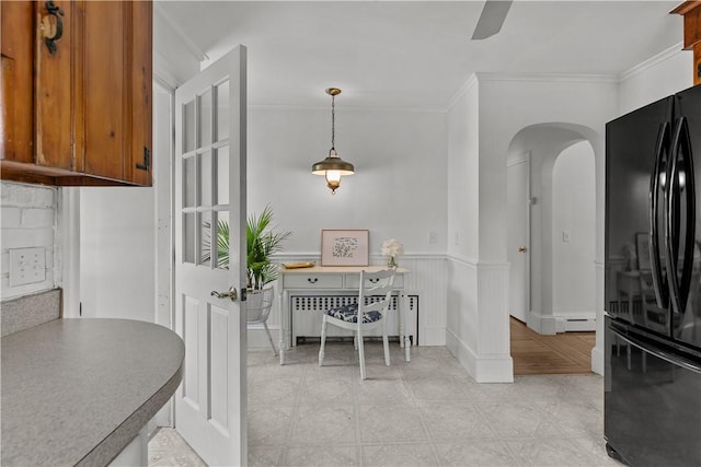 kitchen with radiator heating unit, brown cabinets, arched walkways, ornamental molding, and freestanding refrigerator