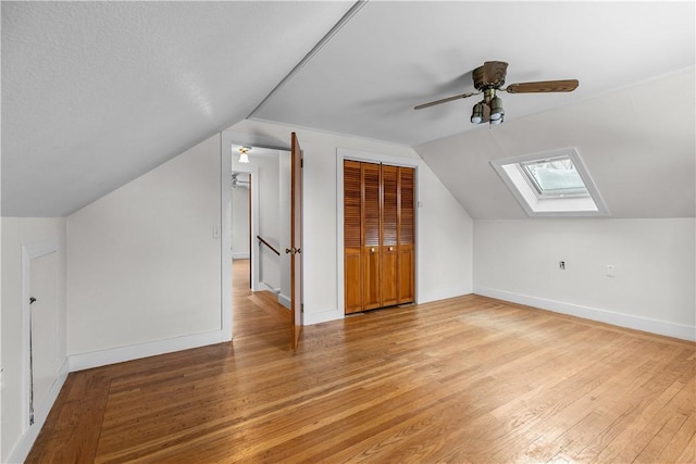 bonus room featuring vaulted ceiling with skylight, a ceiling fan, and baseboards