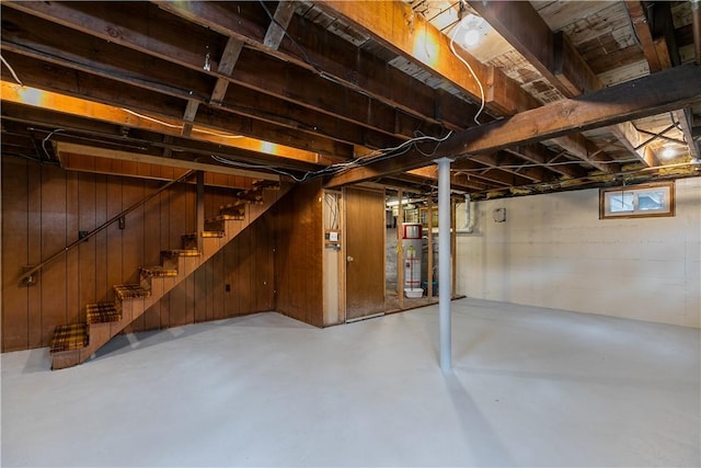 below grade area featuring stairway, wood walls, and gas water heater