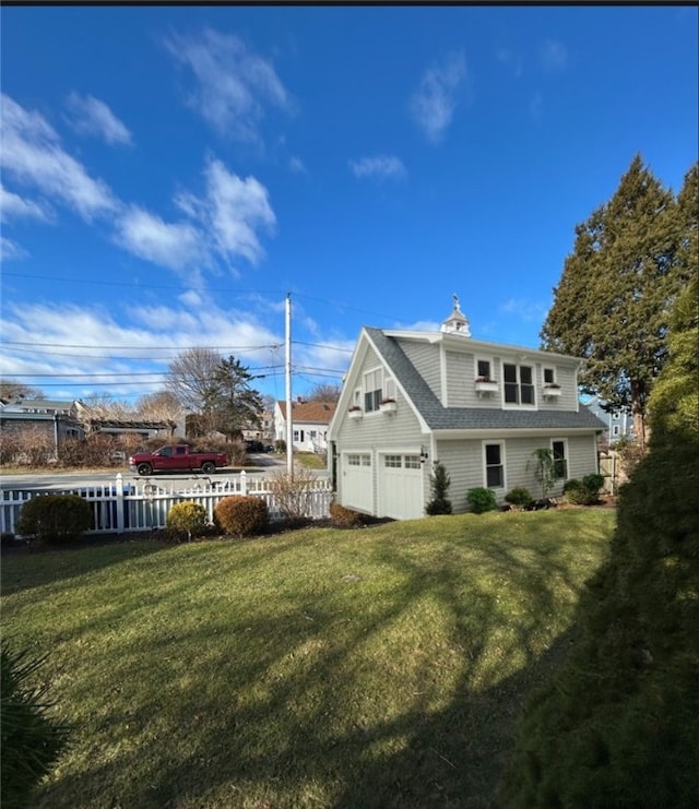 exterior space with fence, a shingled roof, a yard, and a garage