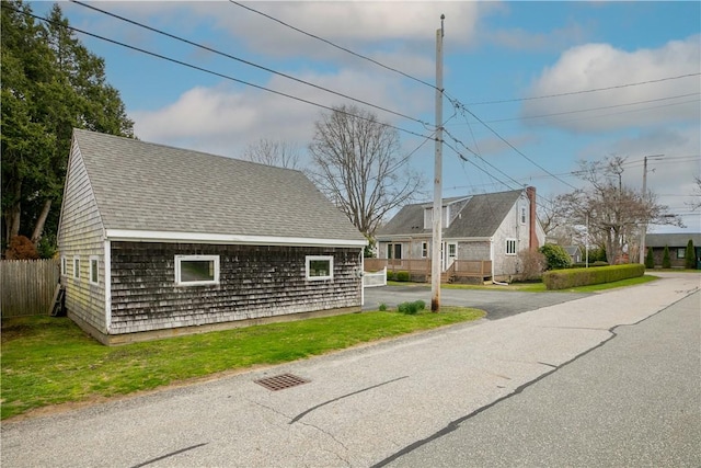 view of front of property featuring roof with shingles, a front yard, and fence