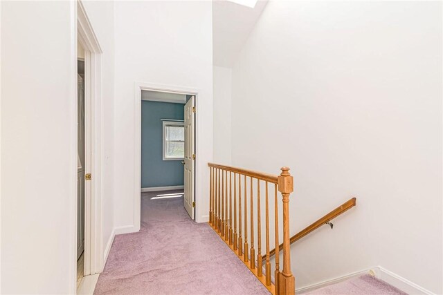 corridor featuring carpet, baseboards, and an upstairs landing