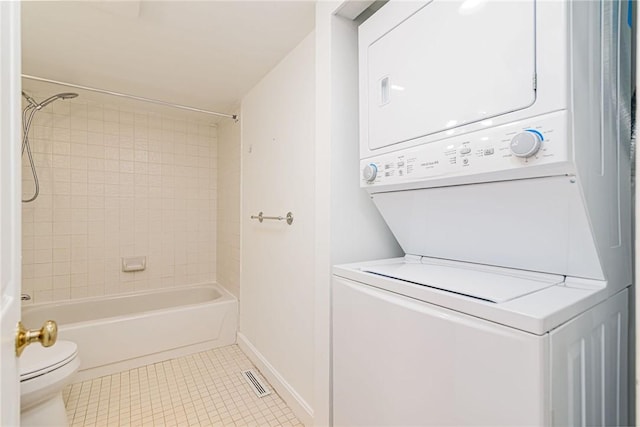 full bathroom featuring toilet, tile patterned floors, stacked washer and dryer, and tub / shower combination