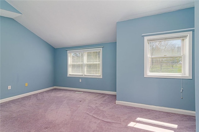 carpeted empty room featuring vaulted ceiling, baseboards, and a healthy amount of sunlight