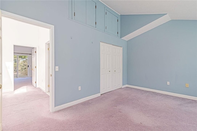 empty room featuring carpet floors, lofted ceiling, and baseboards