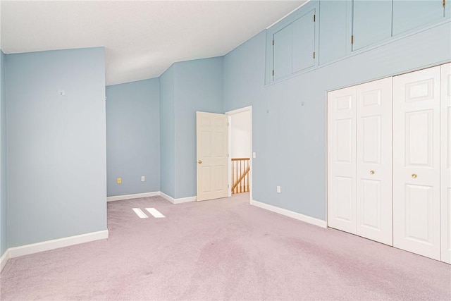 unfurnished bedroom featuring baseboards, light carpet, a high ceiling, and a closet