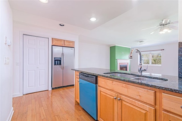 kitchen featuring dark stone counters, a sink, light wood-type flooring, dishwasher, and stainless steel refrigerator with ice dispenser