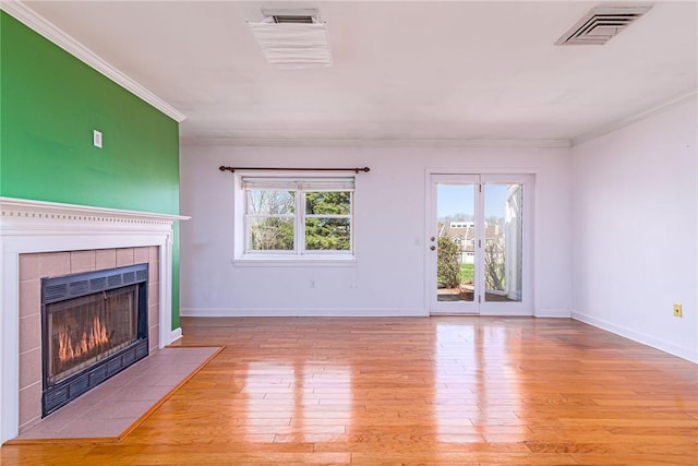unfurnished living room featuring baseboards, visible vents, crown molding, a tile fireplace, and wood-type flooring