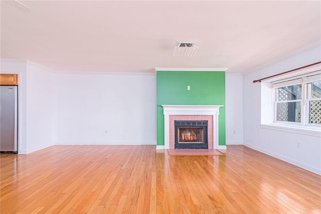 unfurnished living room with baseboards, crown molding, light wood finished floors, and a fireplace