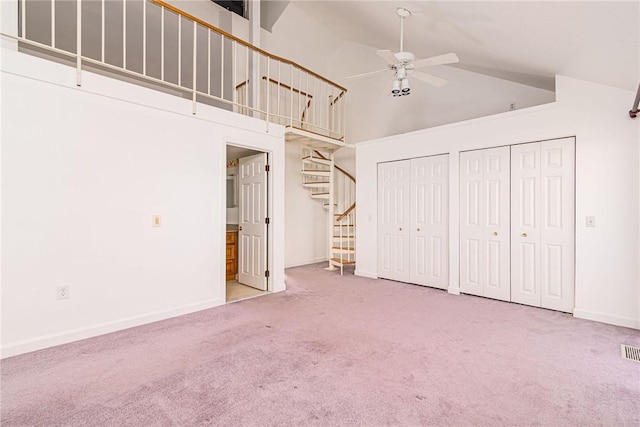 unfurnished bedroom with baseboards, carpet flooring, high vaulted ceiling, and two closets