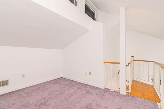 additional living space featuring lofted ceiling, visible vents, carpet flooring, and baseboards