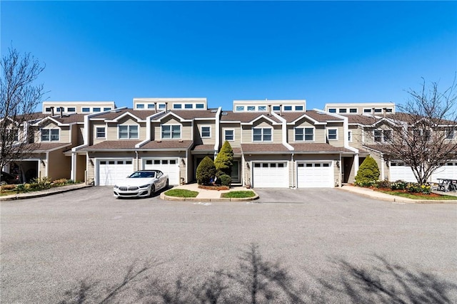 view of property with an attached garage, driveway, and a residential view