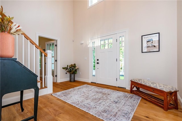 entryway with plenty of natural light, light wood-style flooring, baseboards, and stairway