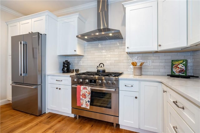 kitchen featuring crown molding, light countertops, appliances with stainless steel finishes, and wall chimney range hood