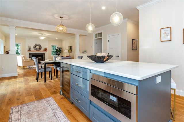 kitchen with blue cabinets, beverage cooler, a large fireplace, and ornate columns
