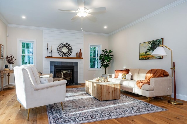 living area with plenty of natural light, a ceiling fan, light wood-style floors, and crown molding