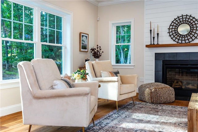living area with a fireplace, wood finished floors, crown molding, and baseboards
