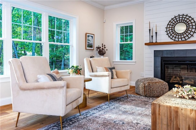 living area with baseboards, a tile fireplace, wood finished floors, and crown molding