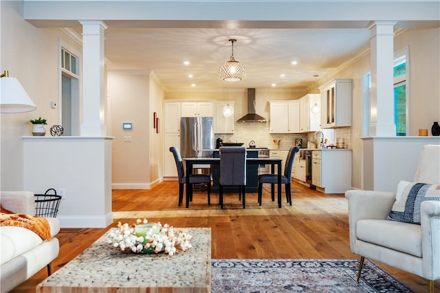 dining area featuring recessed lighting, ornamental molding, baseboards, decorative columns, and light wood-style flooring