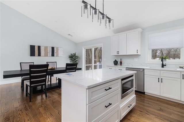 kitchen featuring dark wood finished floors, lofted ceiling, appliances with stainless steel finishes, and a sink