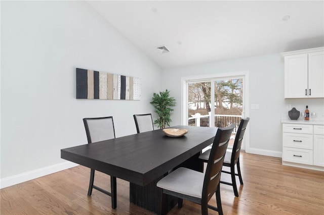 dining room with baseboards, vaulted ceiling, visible vents, and light wood-style flooring