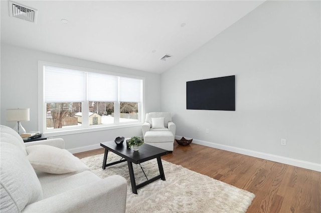living room featuring lofted ceiling, baseboards, wood finished floors, and visible vents