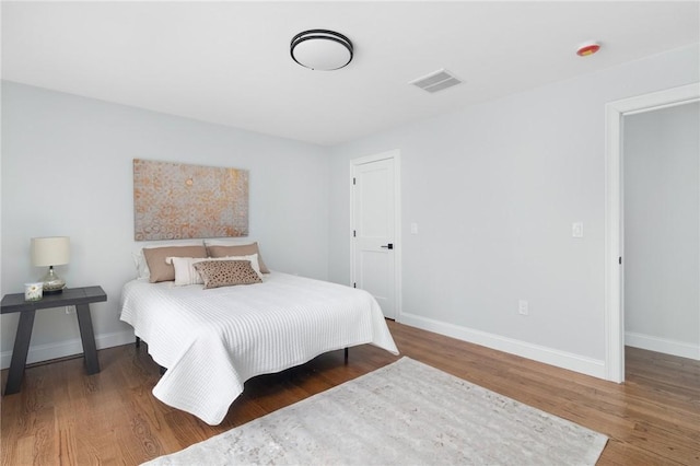 bedroom featuring wood finished floors, visible vents, and baseboards