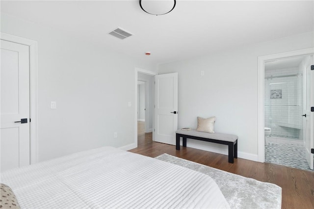 bedroom with baseboards, wood finished floors, visible vents, and ensuite bathroom