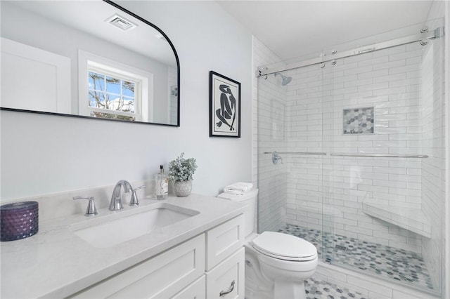 bathroom with toilet, visible vents, vanity, and a stall shower