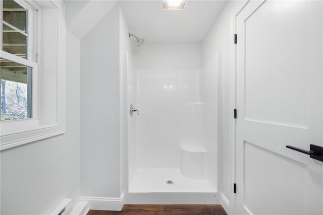 full bathroom featuring baseboard heating, wood finished floors, a stall shower, baseboards, and visible vents