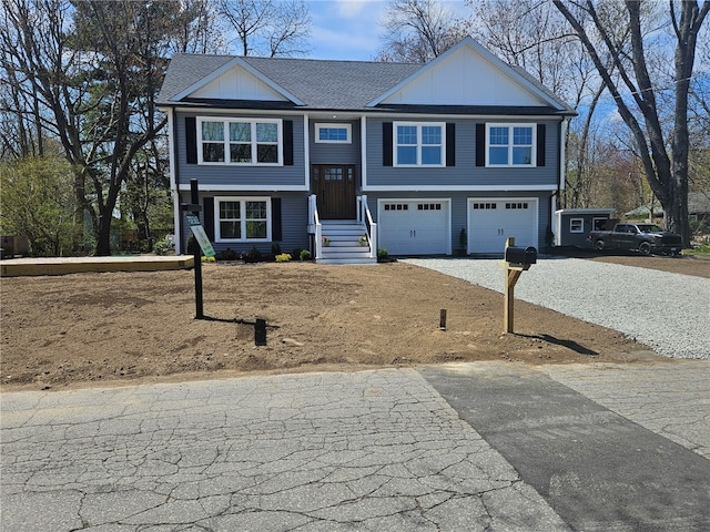 split foyer home featuring board and batten siding, an attached garage, and aphalt driveway
