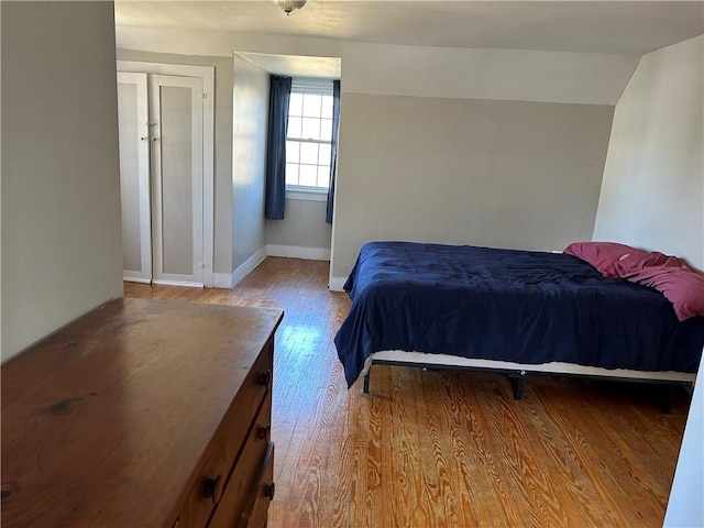 bedroom featuring vaulted ceiling, baseboards, and wood finished floors