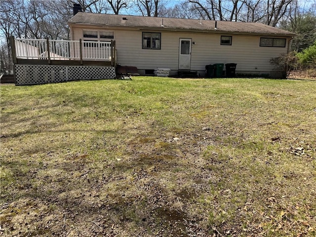back of house with a chimney, a yard, and a deck