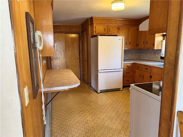 kitchen featuring light countertops, backsplash, brown cabinets, and white appliances